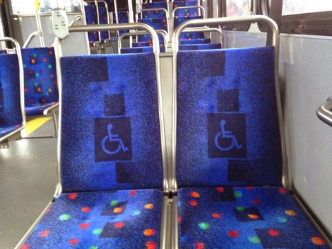 sièges de tram marqués d'un logo pour indiquer que les emplacements sont réservés en priorité à des personnes handicapées